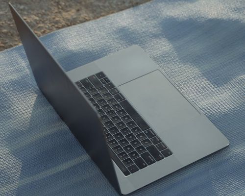 Minimalist laptop and yoga mat setup on dark floor